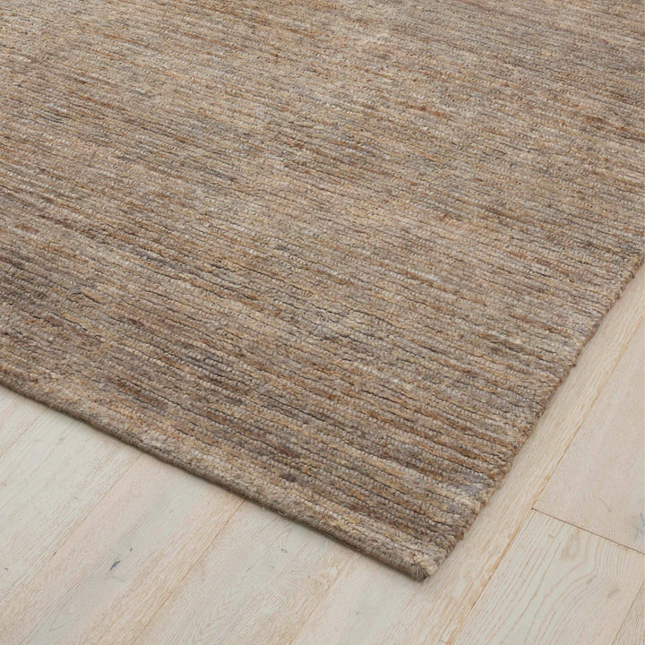 Brown jute textured rug on a light wooden floor
