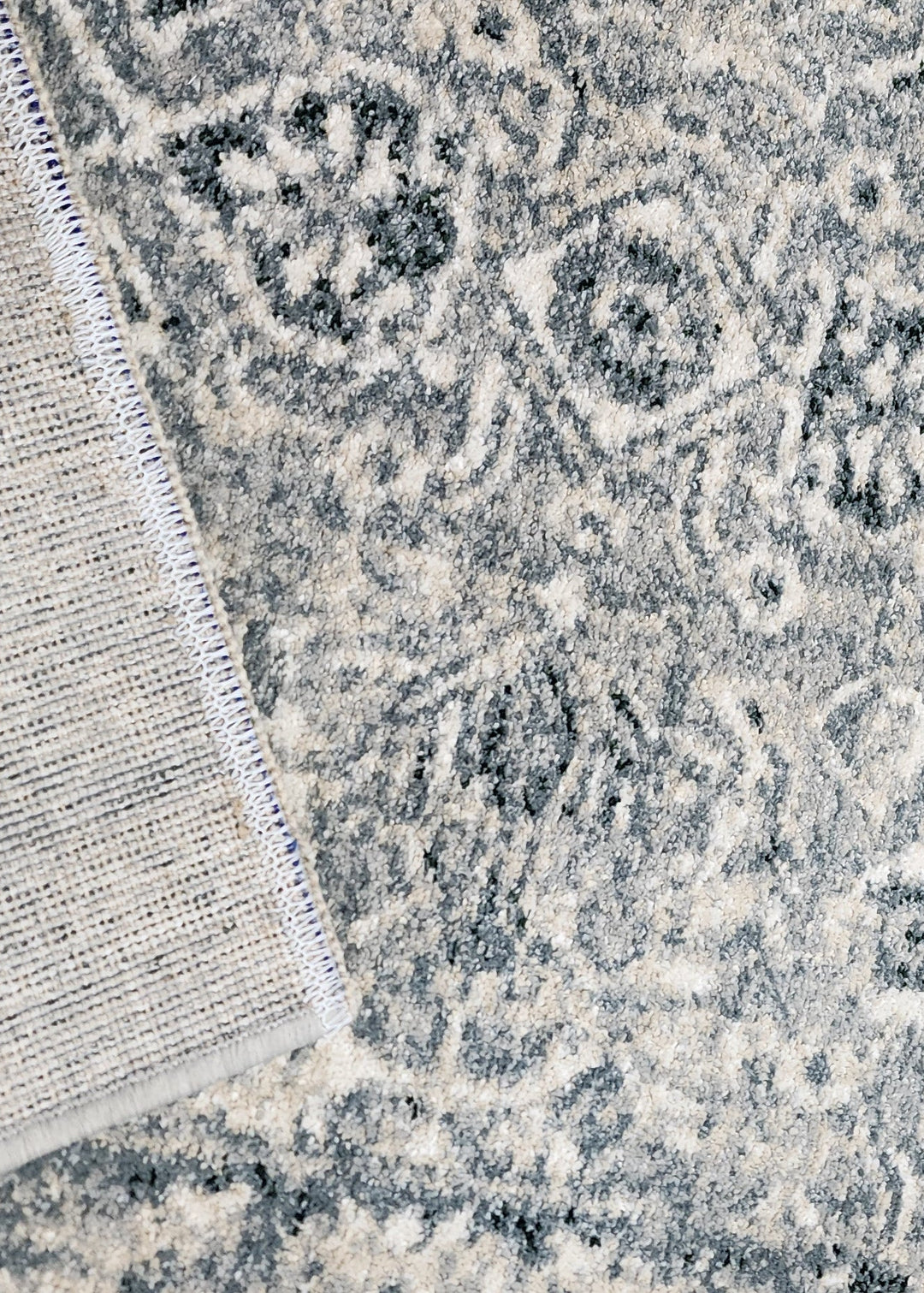 Close-up of a textured rug with intricate patterns and a neutral color palette.