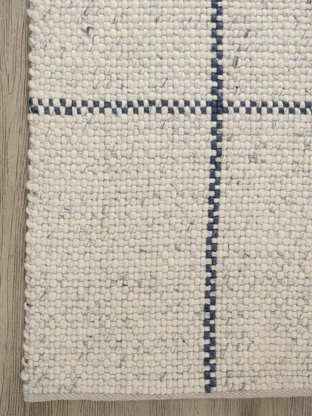 Textured rug with a blue border on a wooden floor