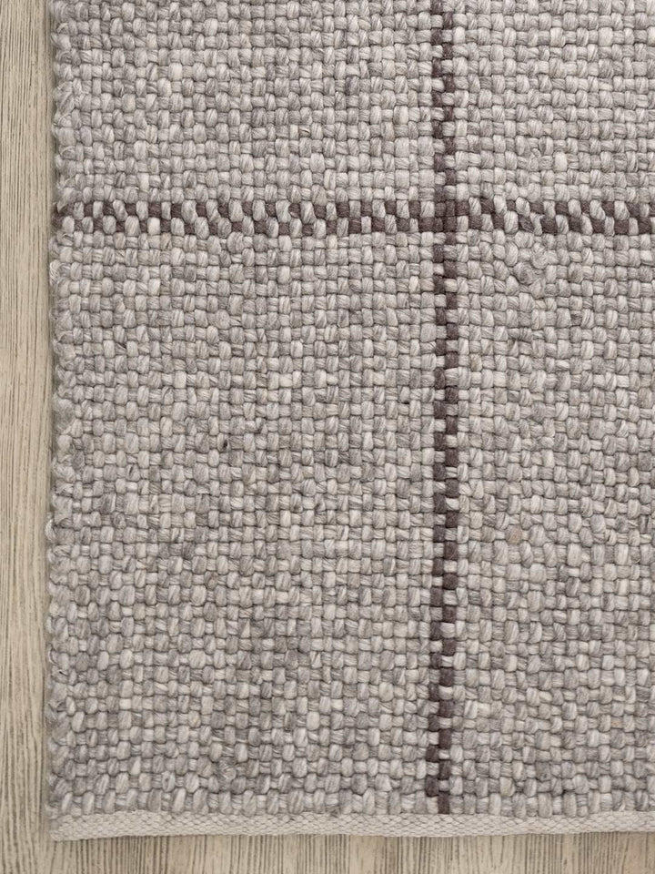 Close-up of a textured rug with a checkered pattern on a wooden floor.