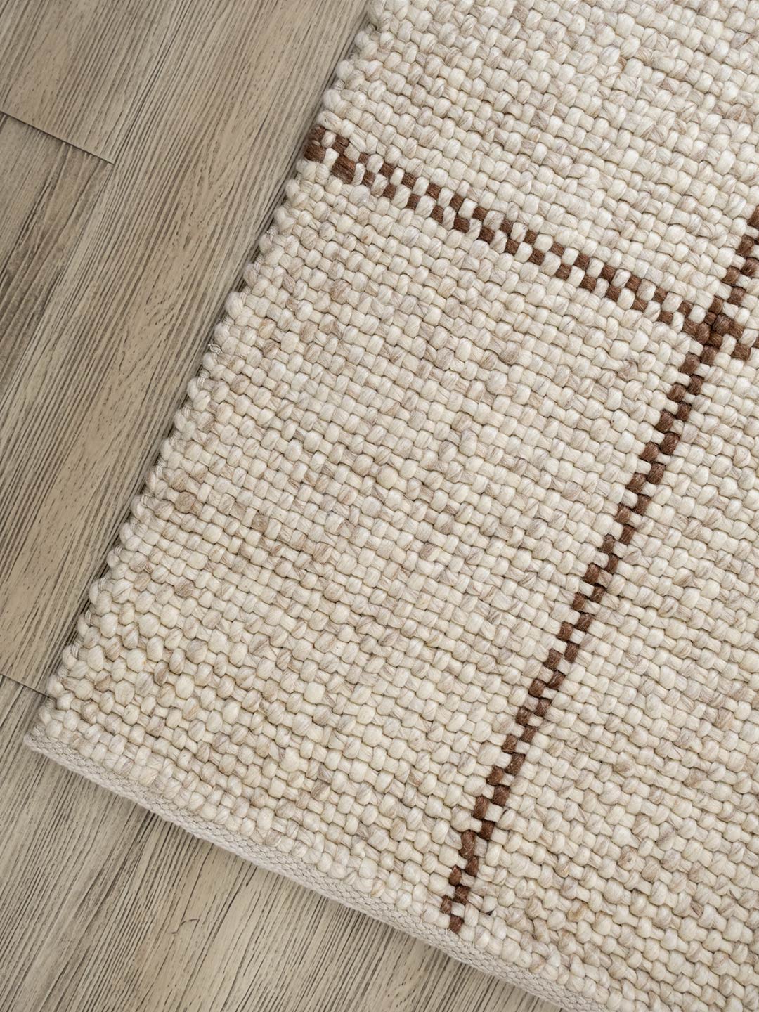 Close-up of a beige woven rug on a wooden floor