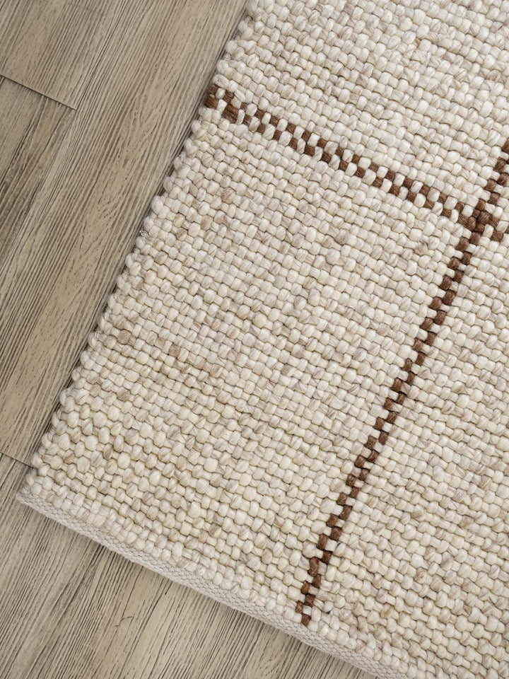 Close-up of a beige woven rug on a wooden floor