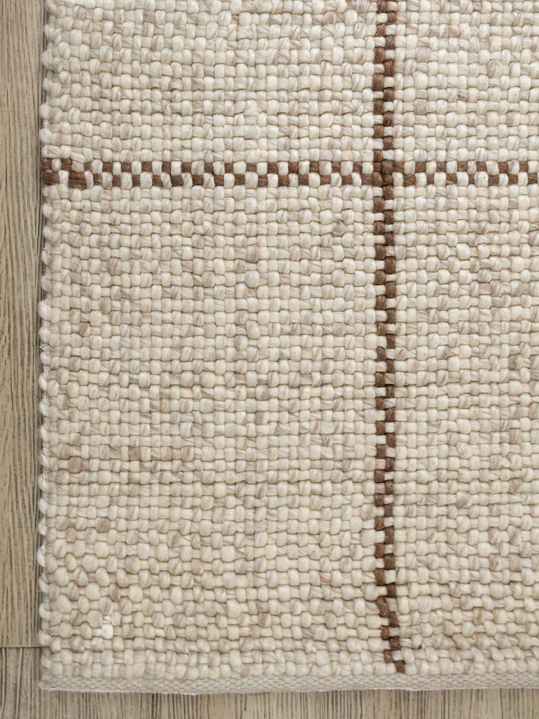 Textured beige rug with brown accents on a wooden floor