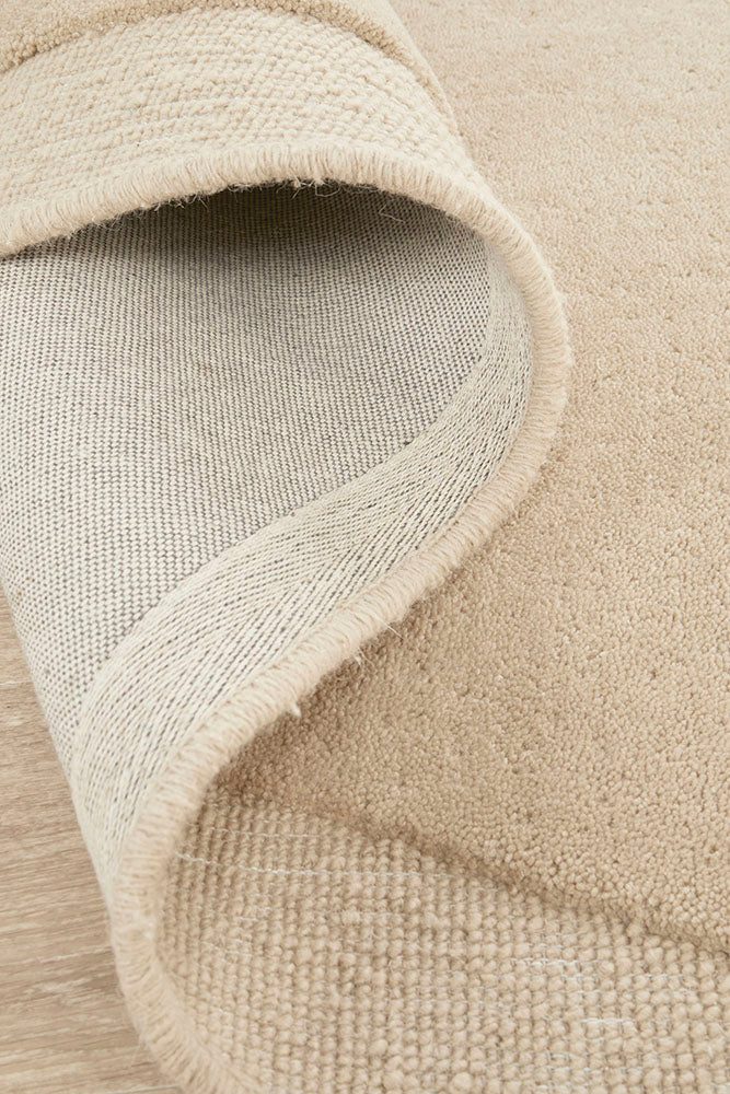 Close-up of a beige textured rug corner on a wooden floor