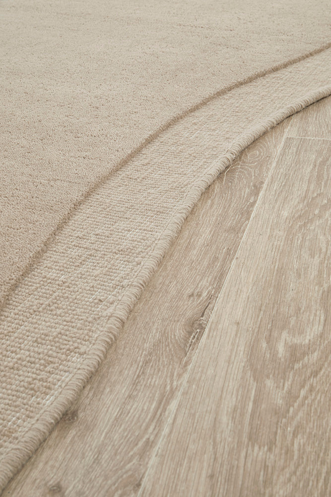 Close-up of a textured beige fabric with a wooden surface underneath
