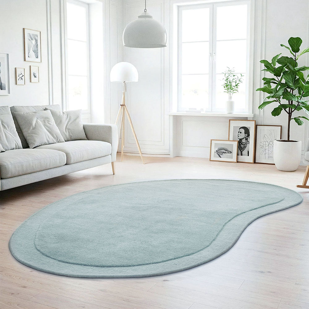 Light blue rug on a wooden floor in a bright living room with a sofa and decor.