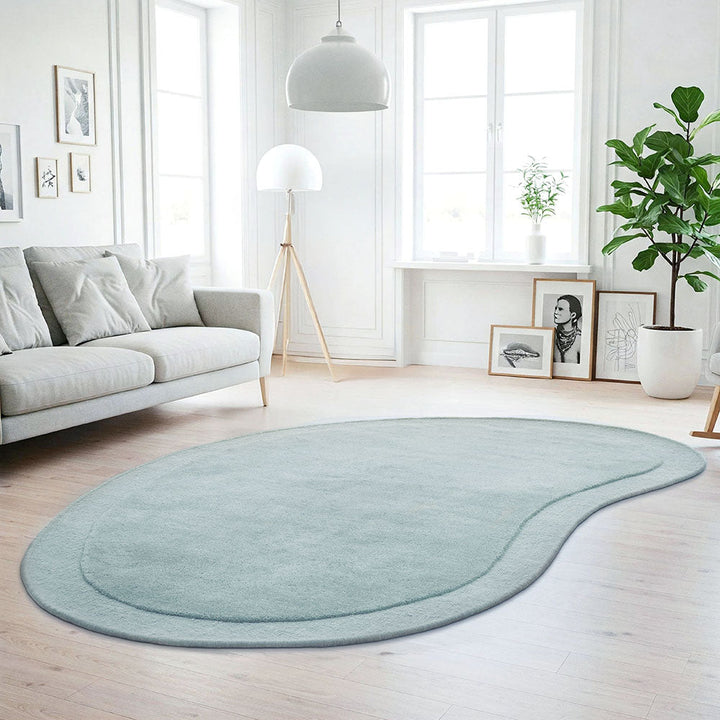 Light blue rug on a wooden floor in a bright living room with a sofa and decor.