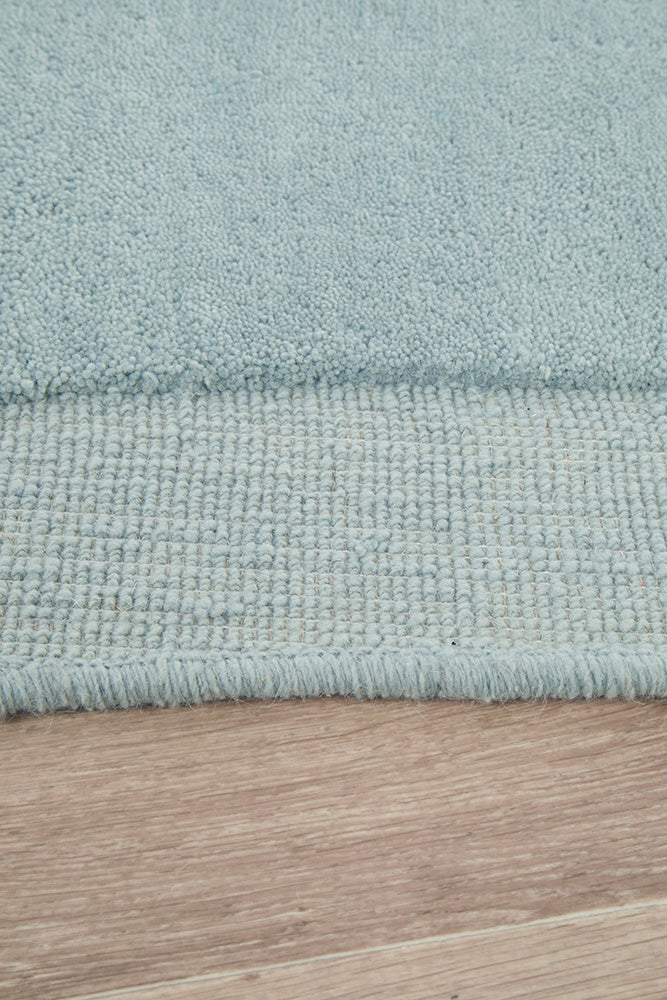 Close-up of a light blue rug on a wooden floor