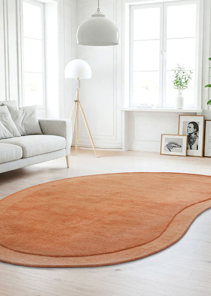 Modern living room with a brown/ orange waterdrop-shaped rug, gray sofa, and decorative elements.