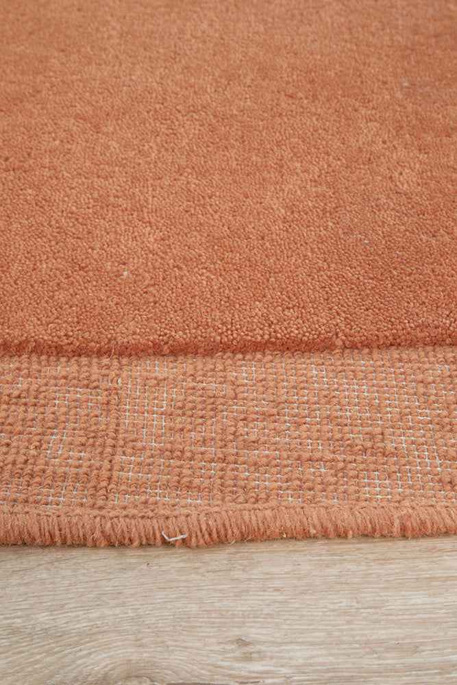 Close-up of a textured orange rug on a wooden floor