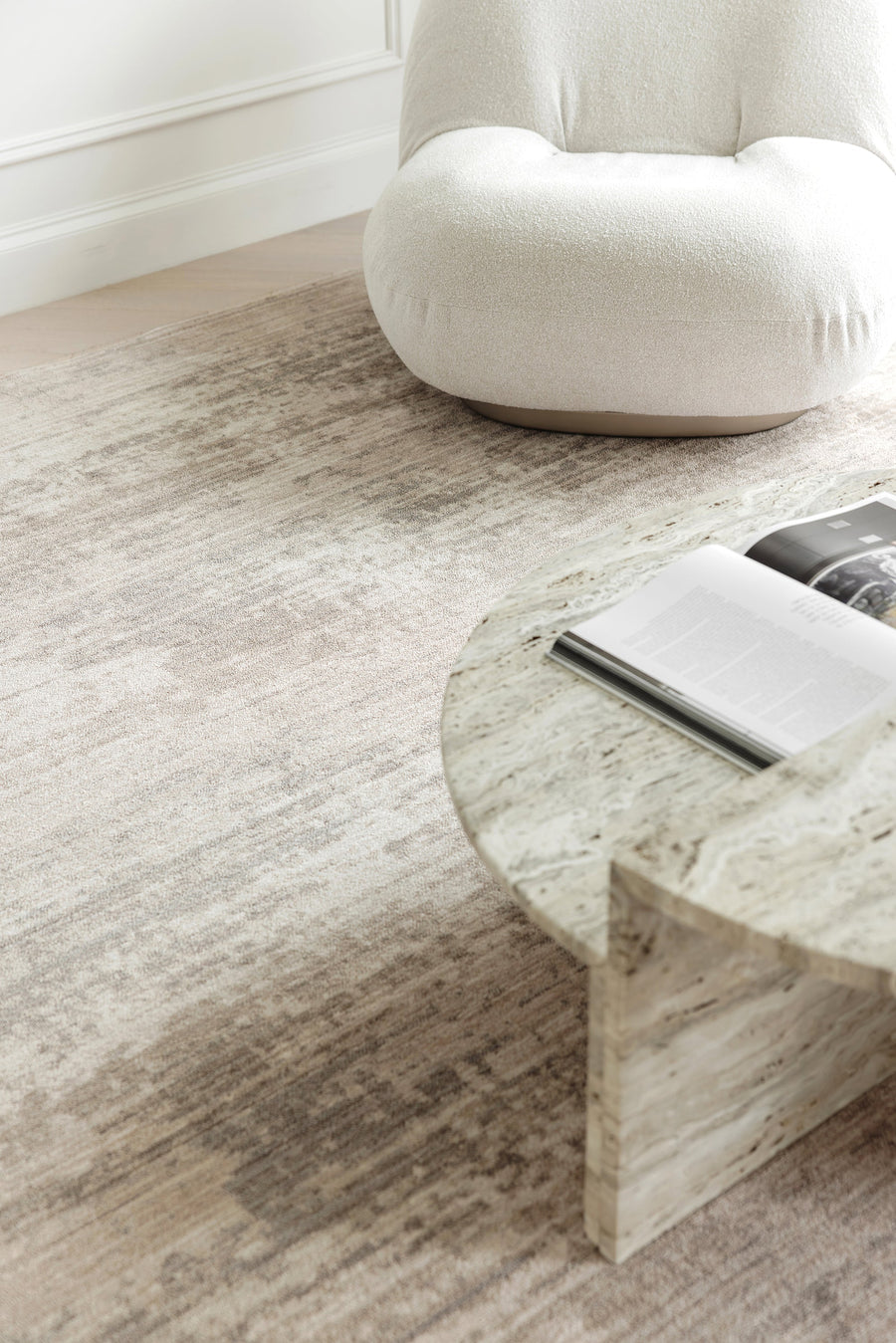 White chair and light oak coffee table on top of a beige and grey colored rug.