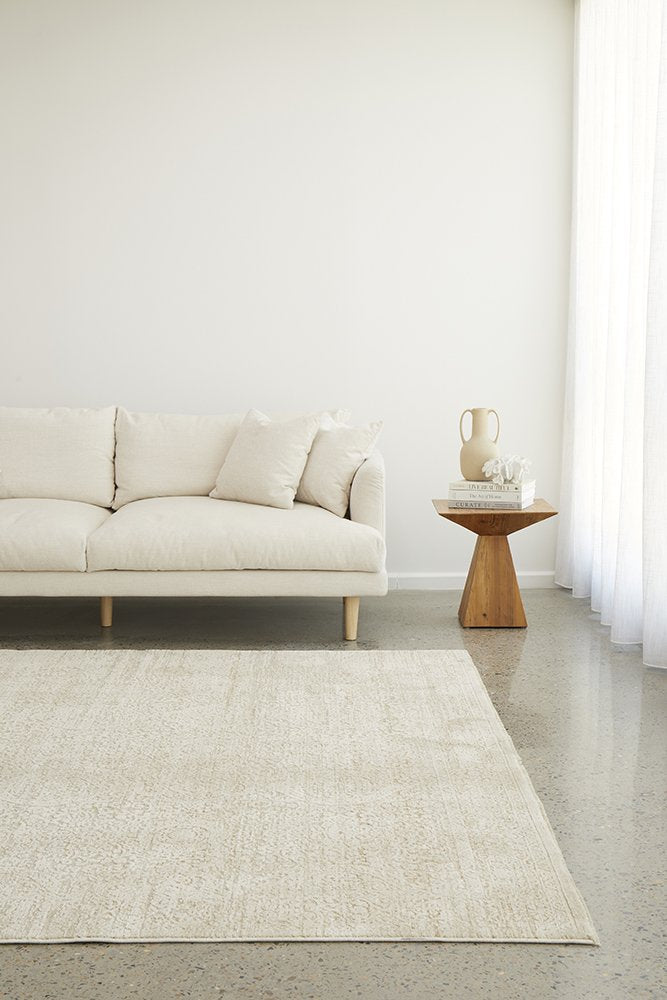 Beige sofa and rug in a minimalistic living room with a wooden side table.