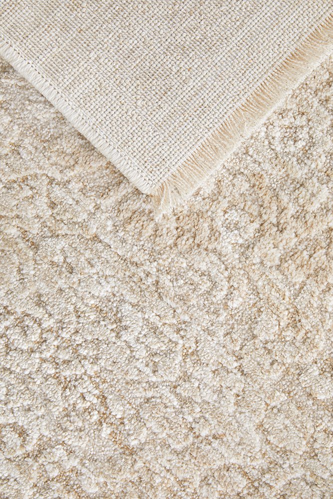 Close-up of a textured beige rug with a folded corner.