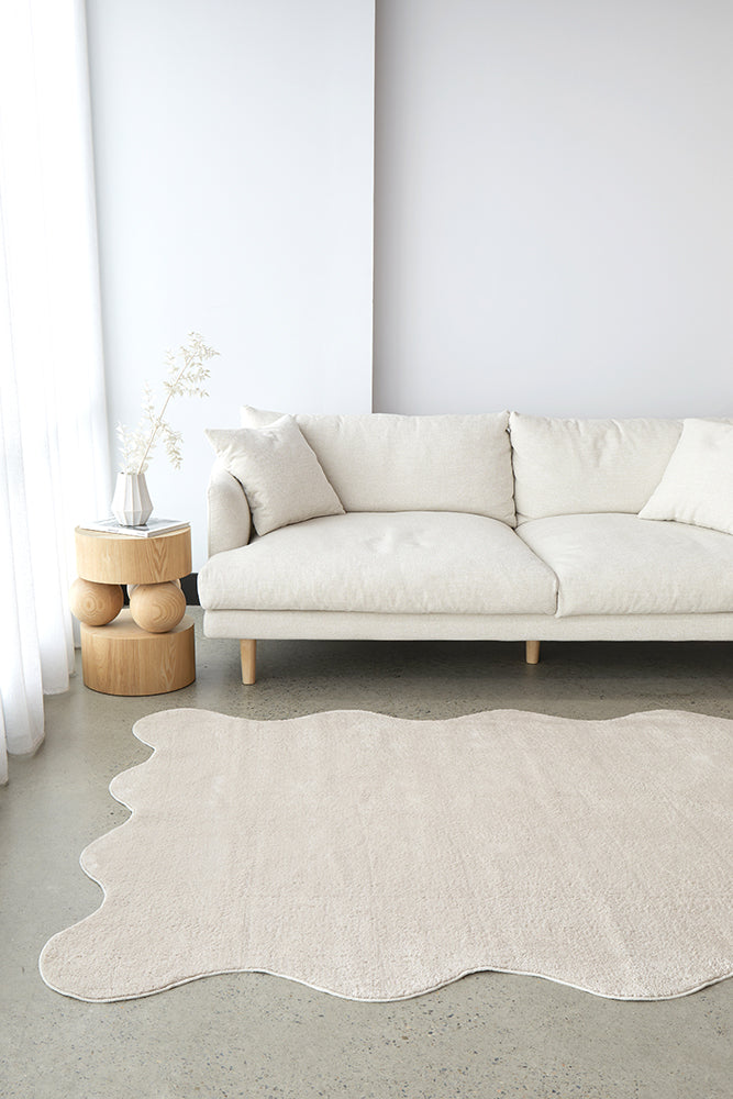 White sofa in a minimalistic living room with a beige rug on the floor.