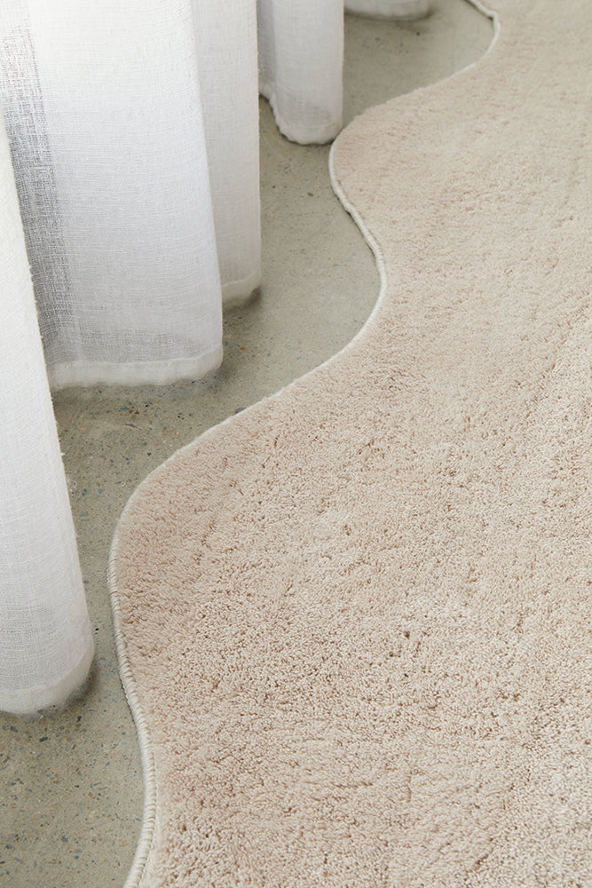 Close-up of a textured beige carpet with white cylindrical objects in the background