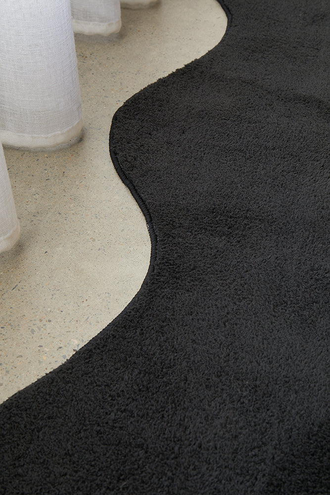 Close up of a black textured rug on a concrete floor