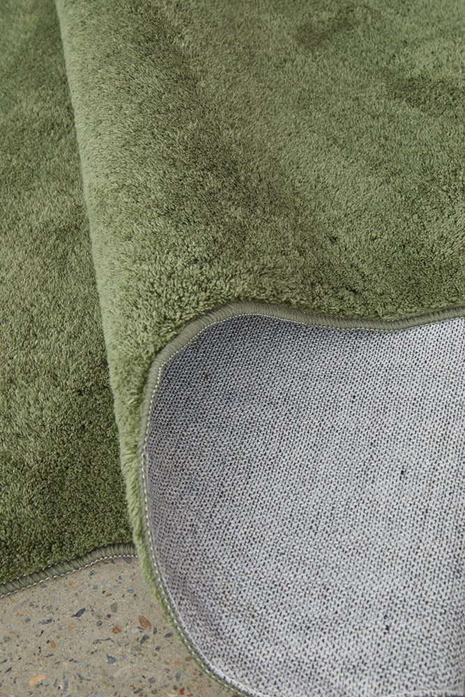 Close-up of a green rug with a textured surface on a concrete floor.