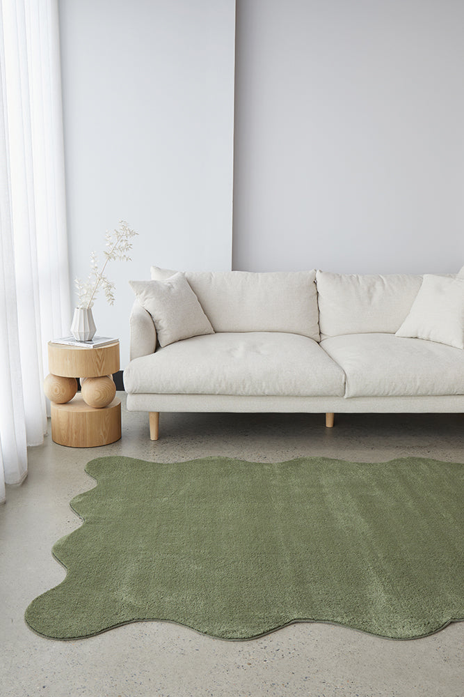 Modern living room with a white sofa and green rug.