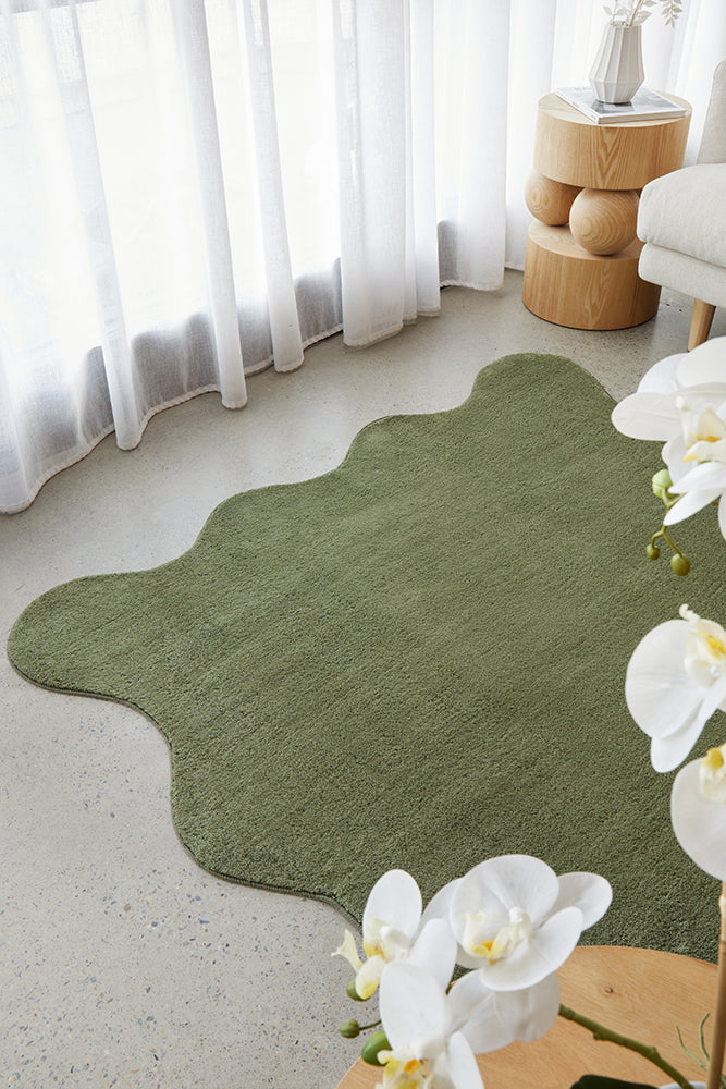 green rug on a concrete floor with white sheers and light timber furniture