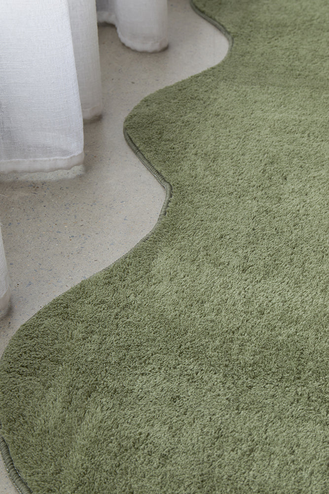 green carved edge rug on a concrete grey floor