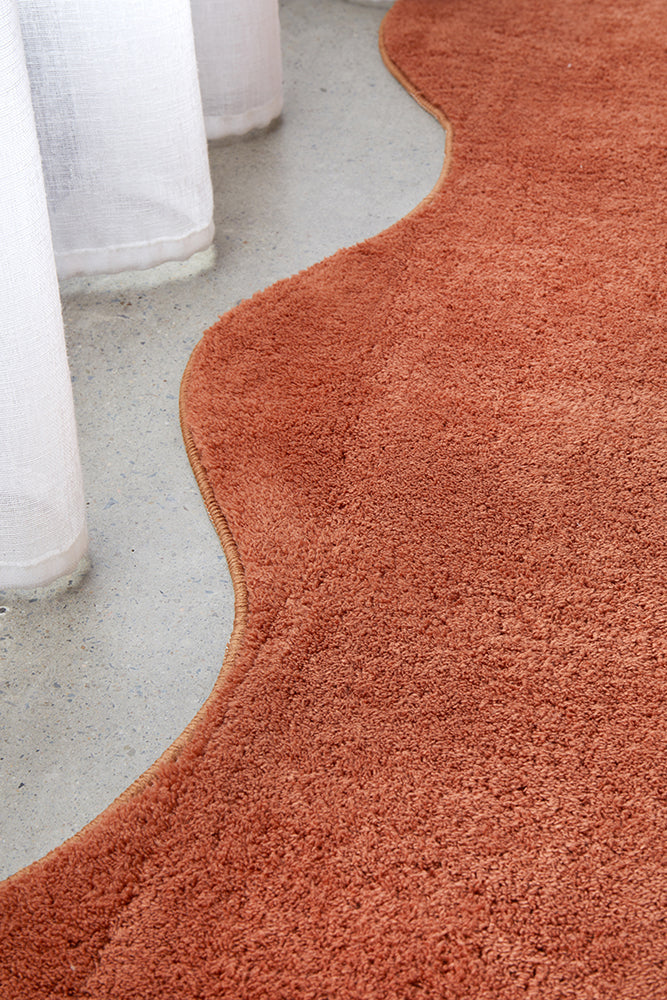 Curved red rug on a concrete floor with white cylindrical objects.