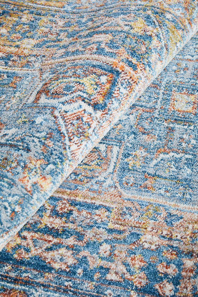 Close-up of a patterned rug with blue, orange, and beige colors.