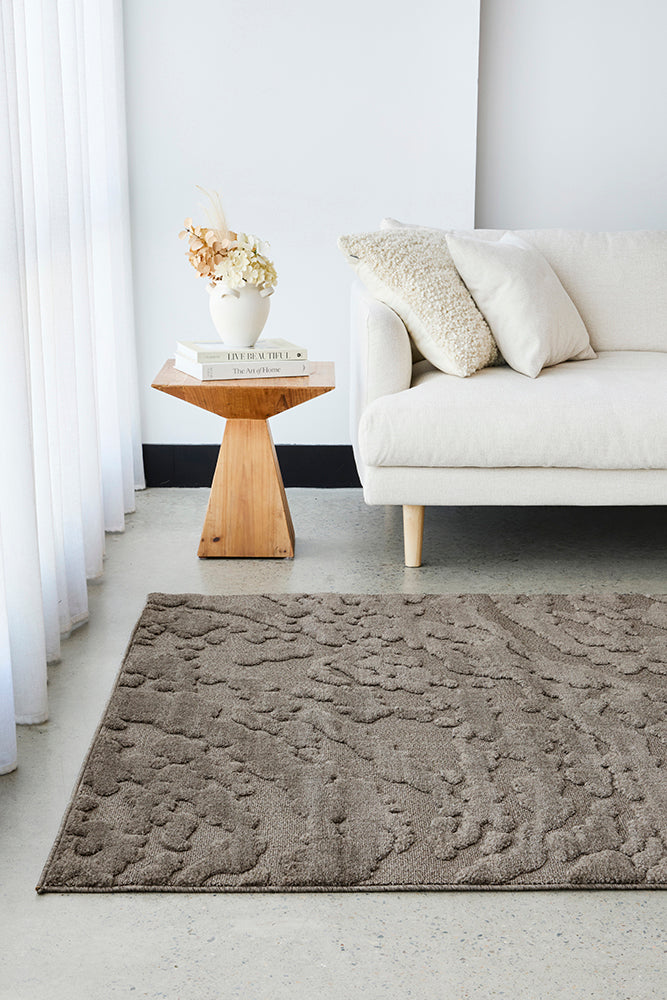Mochas Brown Textured rug on a concrete floor with a linen couch