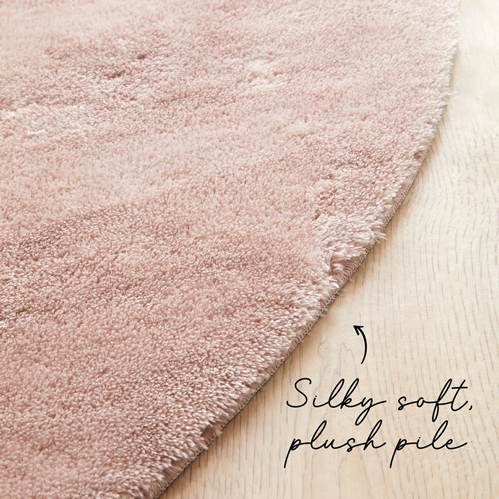 Pink rug on a wooden floor with text 'Silky soft, plush pile'.