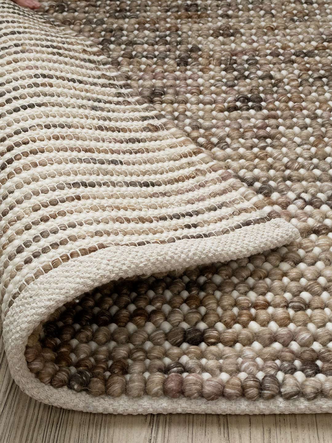 close up of a brown and beige wool rug on a timber floor