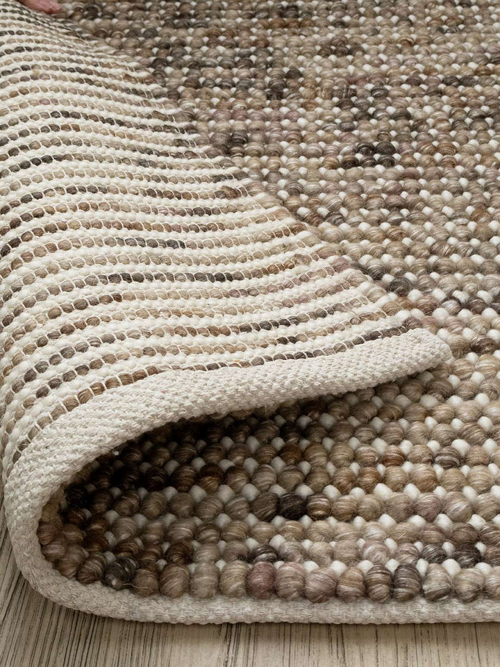 close up of a brown and beige wool rug on a timber floor