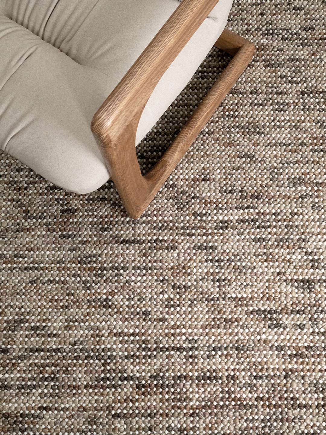 Texture bobble rug in nutmeg colours with a linen and timber accent chair on top

