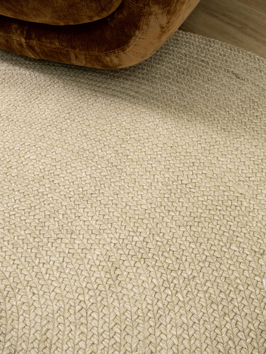 Close-up of textured beige carpet with a brown rug partially visible