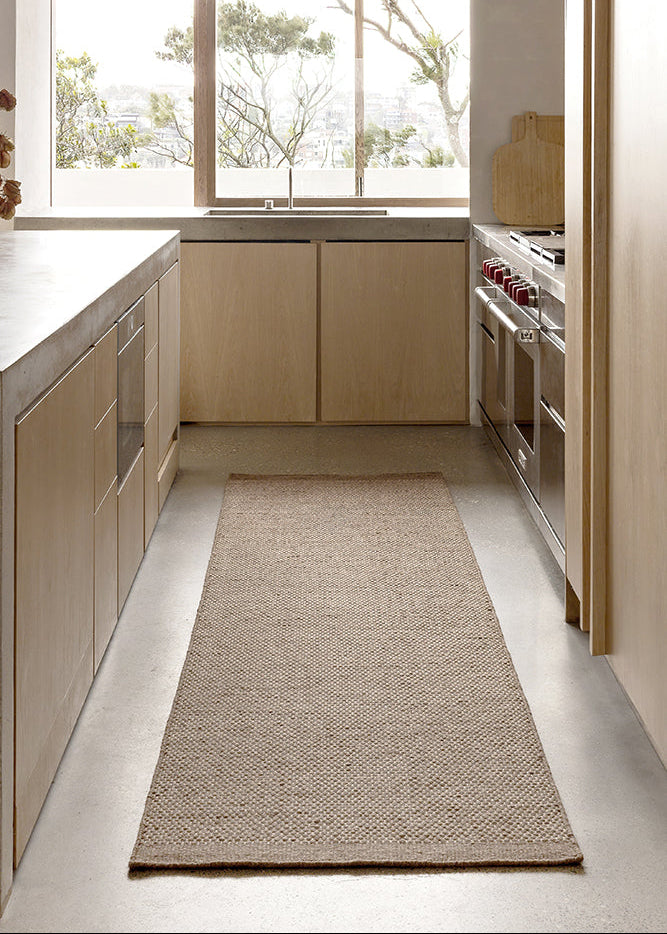 Modern kitchen with wooden cabinets, a Bark Walnut rug on the floor, and a view of trees outside.