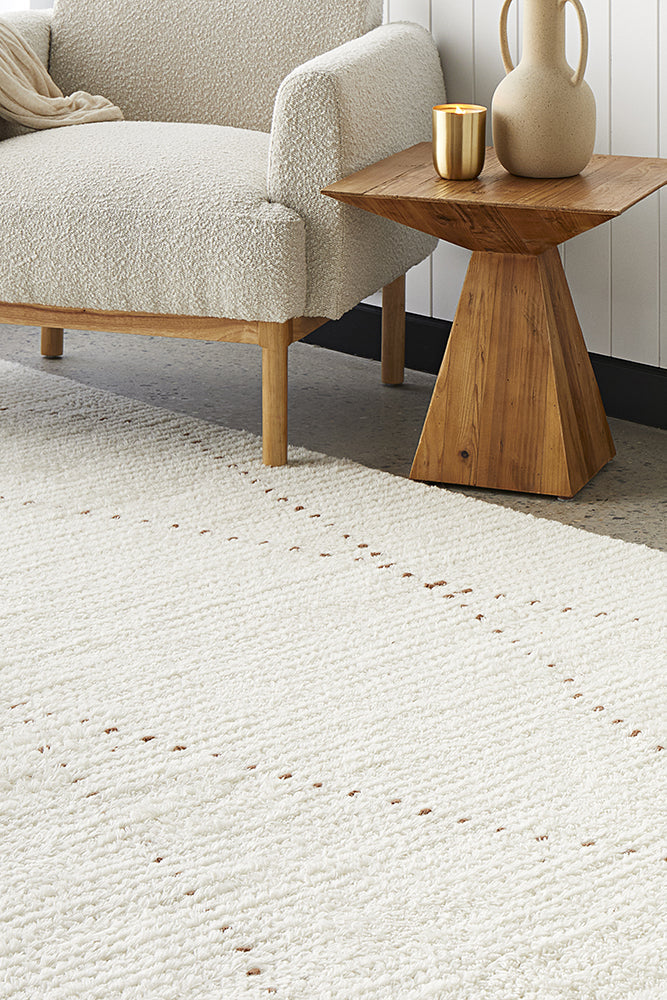 A minimalist rug displayed with a wooden table and chair.